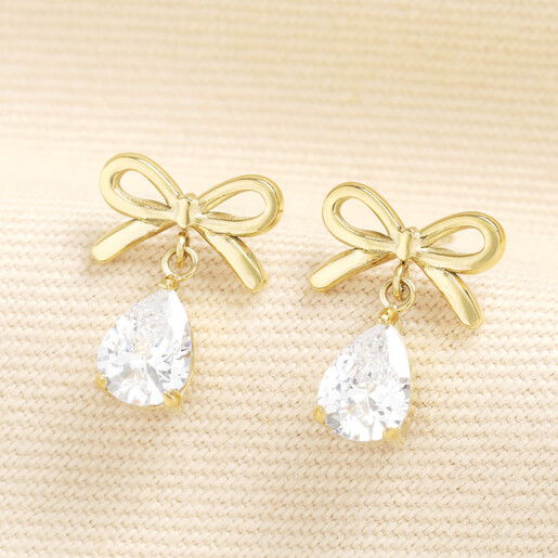 Pair of gold stainless steel bow stud earrings with clear faceted crystal drops