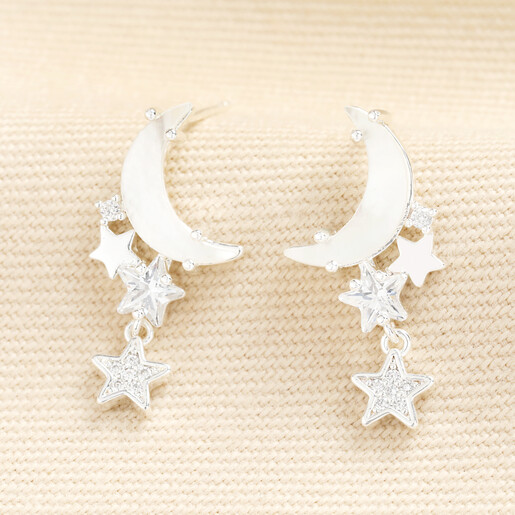 Silver moon and star drop stud earrings on textured fabric