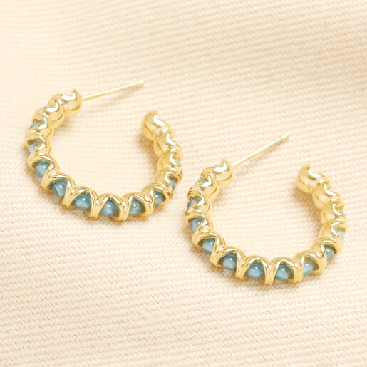 A pair of gold twisted hoop earrings with round turquoise stone beads