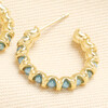 Close-up of a gold stainless steel hoop earring wrapped around turquoise beads