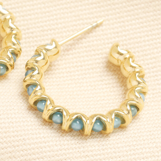 Close-up of a gold stainless steel hoop earring wrapped around turquoise beads