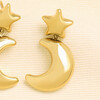 Close-up of a gold stainless steel chunky star and crescent moon drop earring