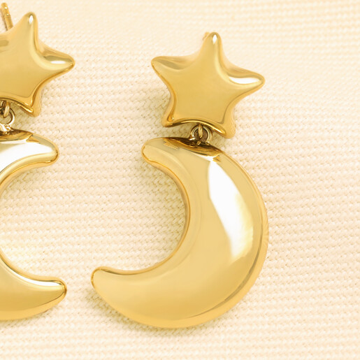 Close-up of a gold stainless steel chunky star and crescent moon drop earring