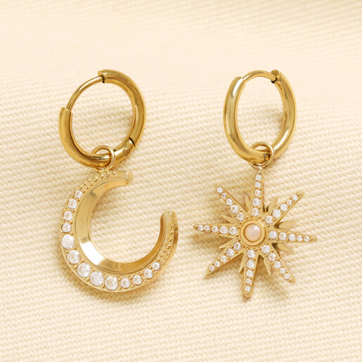 Pair of gold stainless steel mismatched crescent moon and starburst huggie hoop earrings