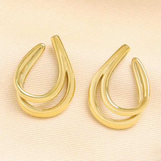 Pair of gold stainless steel double oval chunky hoop earrings on textured cream fabric