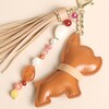 Close-up of tan faux leather dog keyring with neutral tassel and colourful beaded charm