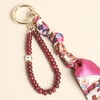 Close-up of red gemstone beads, evil eye charm and silky patterned ribbon on gold clasp