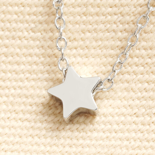 Close up of silver polished star pendant charm on trace chain