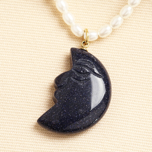 Close up of carved blue sparkly crescent moon face pendant on pearl strand