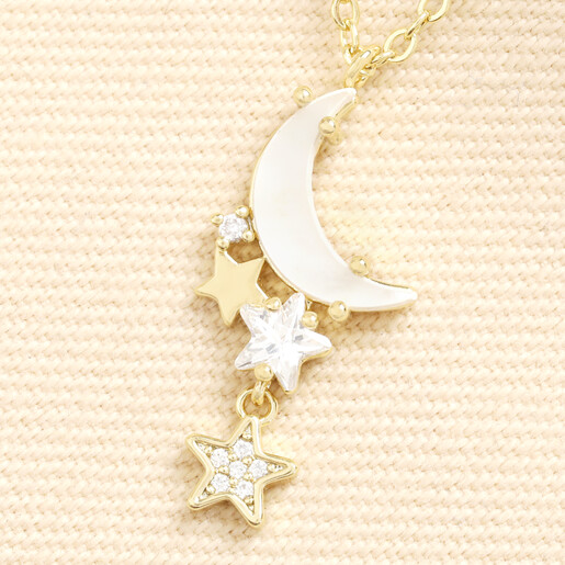 Close-up of gold crescent moon pendant with shell inlay and dangling star charms