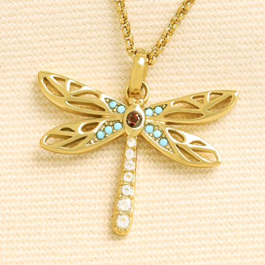 Gold stainless steel dragonfly pendant necklace with crystal accents on a cream background