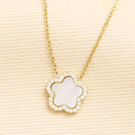 Gold chain necklace featuring a pearlescent flower pendant with crystal border on cream knit