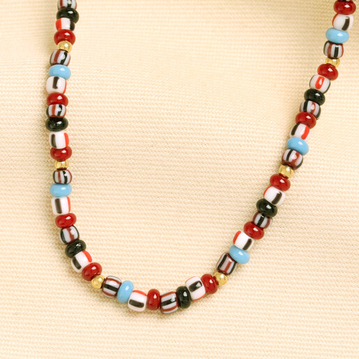 Curved strand of red and powder blue glass beads on textured background