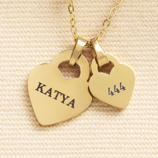 Close up of gold heart charms engraved with Katya and 444