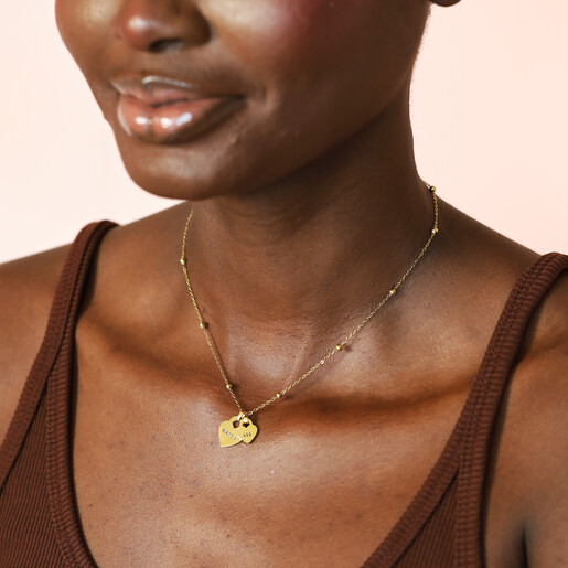 Woman wearing delicate gold beaded chain necklace with engraved heart pendants