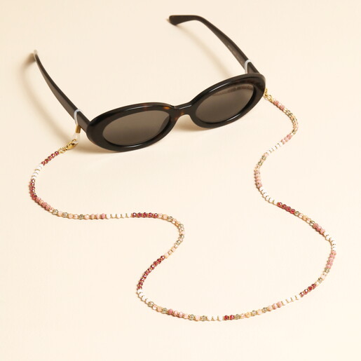 Pink and red semi precious beaded glasses chain attached to sunglasses on cream background