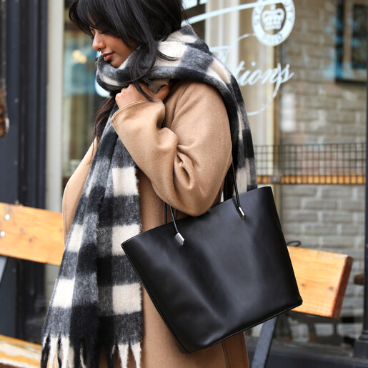 Woman wearing black and white checkerboard winter scarf with black handbag