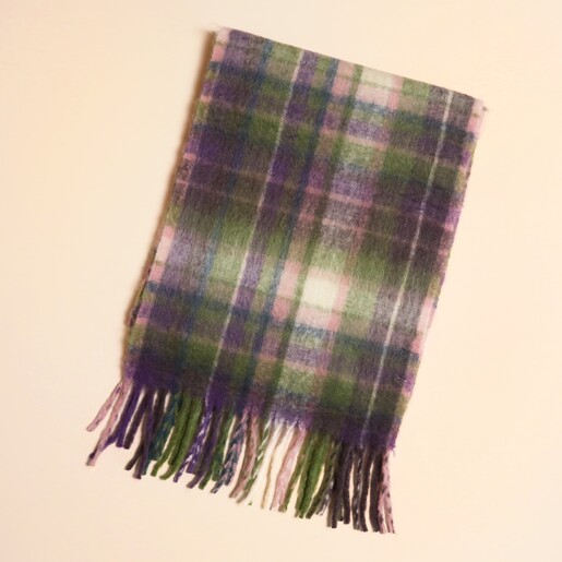 Folded purple and green tartan winter scarf with fringed edges