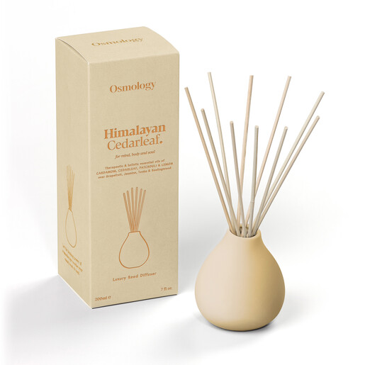 Osmology Himalayan Cedarleaf diffuser with natural wooden reeds beside product gift box