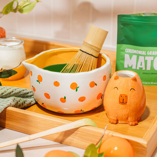 Ceramic matcha bowl with whisk and capybara holder on a wooden tray