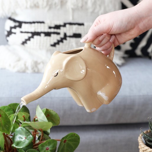 A Cream Glazed Ceramic Elephant Watering Jug With Water Being Poured onto a Plant from the Spout