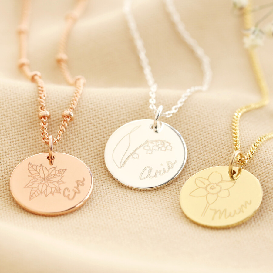 Personalised Engraved Birth Flower Disc Necklace on top of beige coloured fabric