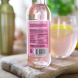 bottle of artisan drinks co pink citrus tonic with ingredients label and glass and cocktail shaker in background