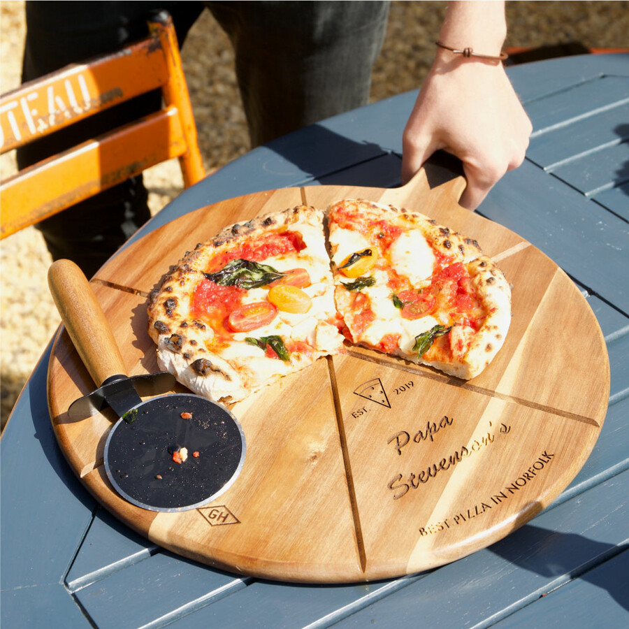 Personalised 'Est.' Pizza Serving Board & Cutter Set on top of table with dad using