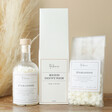 The Annex Paradise Wax Pearls bottle, diffuser and bag on a brown table in front of pampas grass