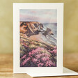 Coastline Painting Greeting Card stook on table in front of green background