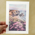 Model holding Coastline Painting Greeting Card in front of a green background