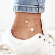 model wearing Personalised Set of Two Freshwater Pearl and Disc Anklets in Gold anklet is blackened engraved with initial A