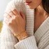 Model Wearing Crystal Daisy Charm Bracelet in Gold Layered with Other Bracelets