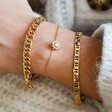 Model Wearing Delicate Crystal Daisy Charm Bracelet in Gold Layered with Other Bracelets
