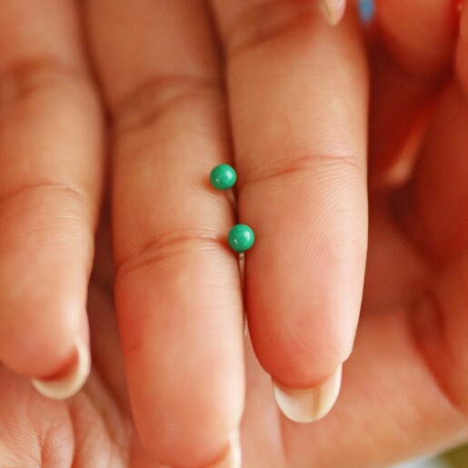 model holding Green Ball Stud Earrings in Gold between fingertips