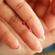 model holding Red Ball Stud Earrings in Gold between their fingers