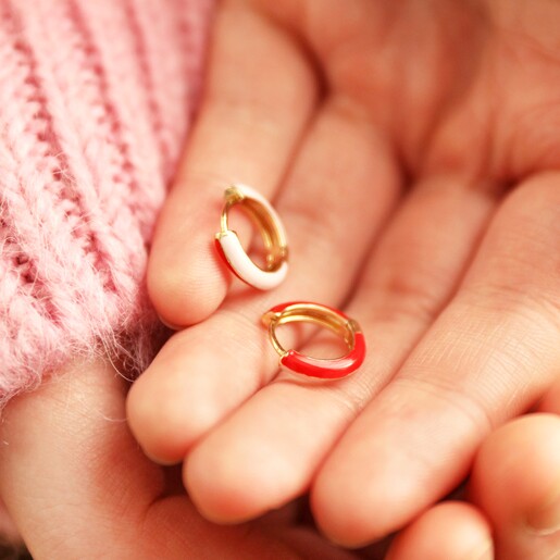 Model Holding Enamel Huggie Hoop Earrings in Red and Pink