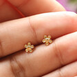 Model Holding Tiny Flower Stud Earrings in Gold