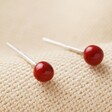 Red Ball Stud Earrings in Gold on fabric background