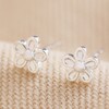 Tiny Flower Stud Earrings in Silver on Beige Fabric