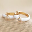 White Enamel Crystal Huggie Hoop Earrings in Gold on Beige Fabric