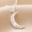 Close Up of Crystal Crescent Moon Necklace in Silver on Beige Fabric