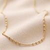 Gold Satellite Chain Necklace on Beige Fabric
