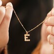 Model Holding Hammered E Initial Charm Necklace in Gold