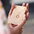 Crystal Sunburst Pendant Necklace in Gold on Packaging Held by Model