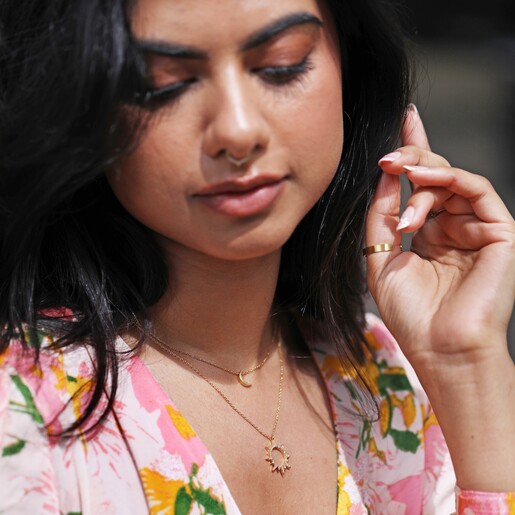 Model Wearing Crystal Sunburst Pendant Necklace in Gold Layered with Other Necklace