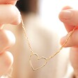 Model holding Figaro Chain and Heart Outline Necklace in Gold