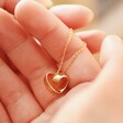 Model Holding Infinity Heart Knot Necklace in Gold
