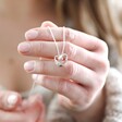 Model Holding Infinity Heart Knot Necklace in Silver