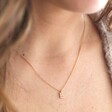Close Up of Model Wearing Tiny Pearl Initial Charm Necklace in Gold